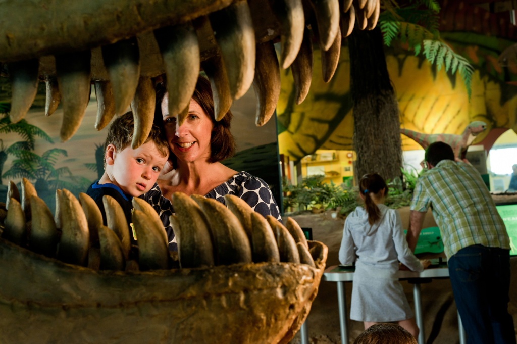 Mother and child in museum looking through dinosaur jaws.